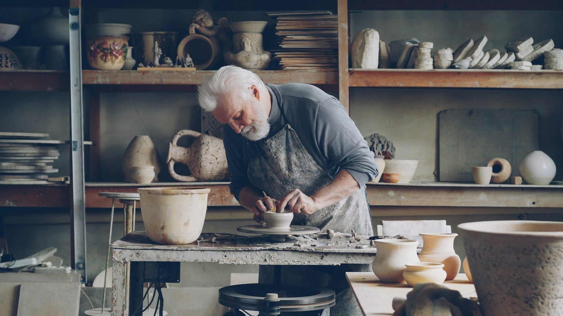Patyręs vyras keramikas dirbtuvėse gamina molio indus ant puodžiaus rato dirbancio pensininko atleidimas is darbo 1