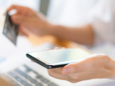 Rankos kuriose laikoma kredito kortelė naudojantis nešiojamuoju kompiuteriu ir mobiliuoju telefonu kada mokama bedarbio pasalpa