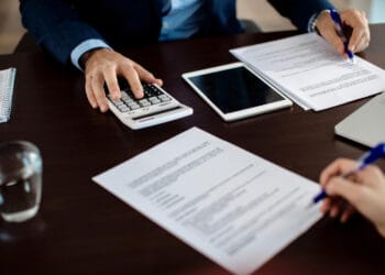 Finansų konsultanto tvarkančio dokumentus per susitikimą su klientu stambiu planu