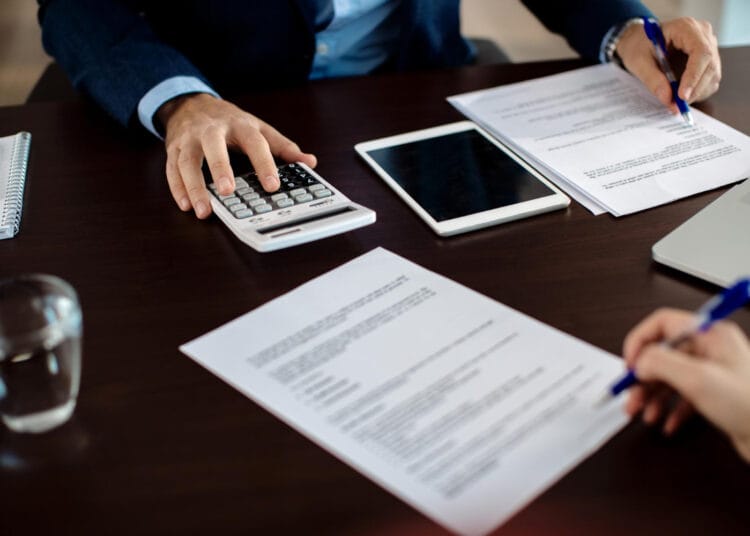 Finansų konsultanto tvarkančio dokumentus per susitikimą su klientu stambiu planu