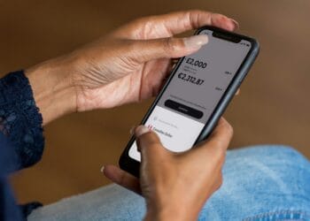 Išmanųjį telefoną laikančios rankos naudojančios banko programėlę pinigams pervesti kiek galima pervesti pinigu be mokesciu