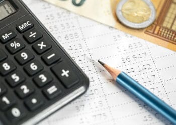 Skaičiuoklės pinigai ir pieštukas stambiu planu neryškiame fone individualios veiklos mokesciai