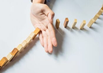 Verslininkas ranka sustabdyti domino nuolat nuverstas arba rizika su copyspace