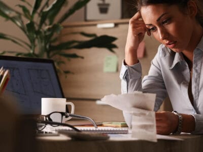 Verslininkė dirbdama biure jaučianti nerimą dėl finansinių skolų ir analizuojanti sąskaitas išeitinė išmoka atleidžiant iš darbo