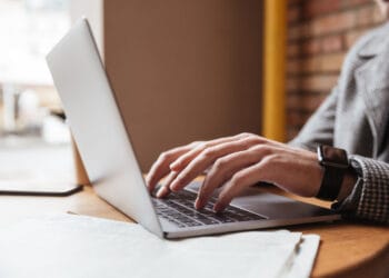 Apkarpytas verslininko su akiniais sėdinčio prie stalo kavinėje ir besinaudojančio nešiojamuoju kompiuteriu vaizdas Kaip uždaryti individualią veiklą