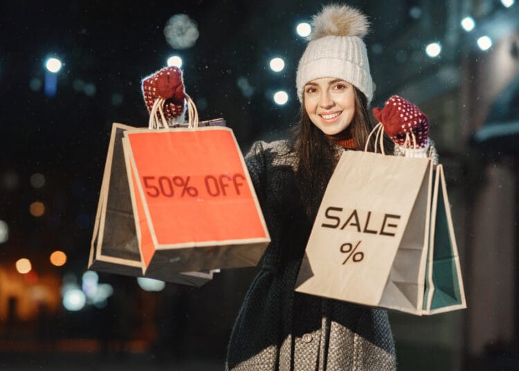 Jaunos moters su pirkinių krepšiais naktinis portretas lauke