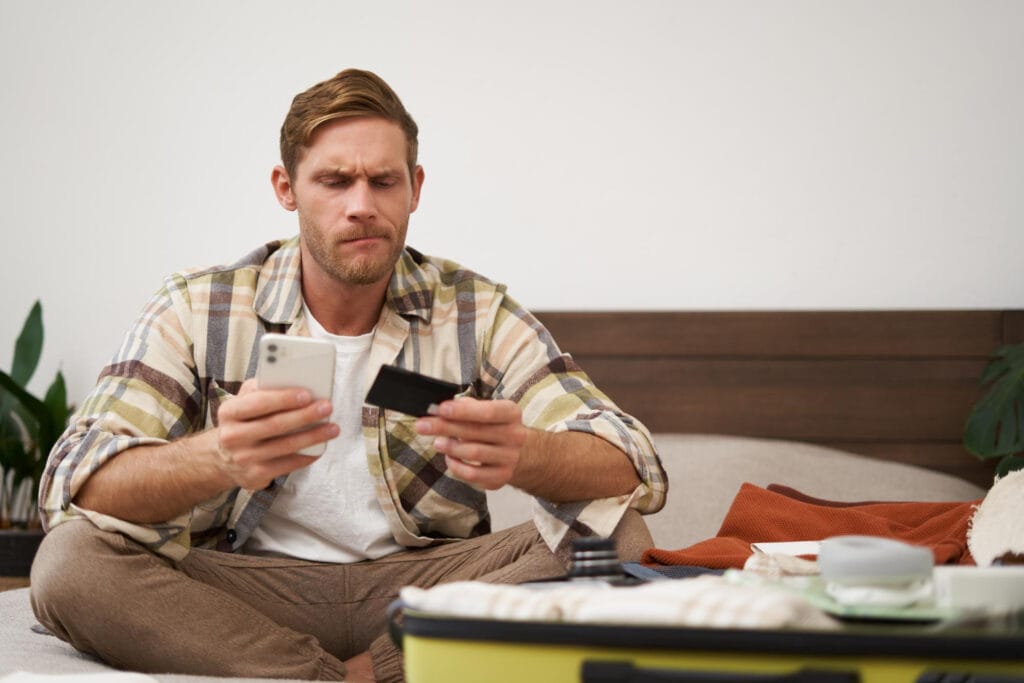 Laimingo vyro su lagaminu pervedančio pinigus ir perkančio bilietus internetu sėdinčio ant lovos portretas kada nereikia moketi psd