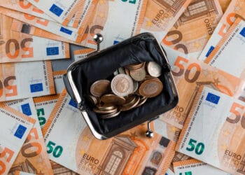 Monetos piniginėje ant banknoto ir gipsinio stalo