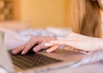 Moteris dirbanti su nešiojamuoju kompiuteriu stambiu planu