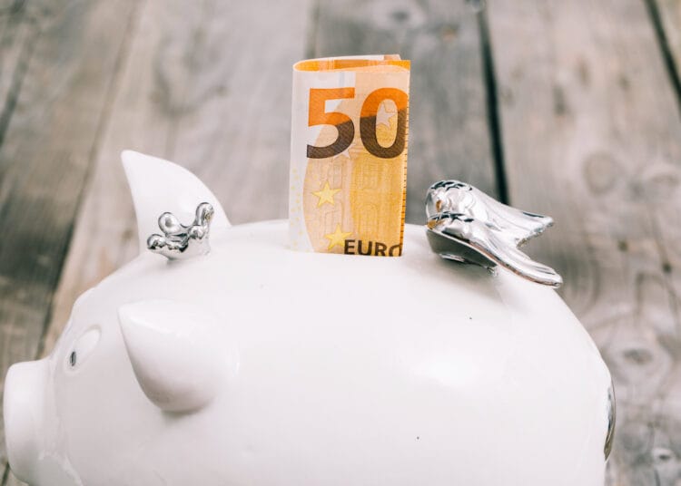 Stambiu planu sulankstytas penkiasdešimties eurų banknotas baltos taupyklės lizde