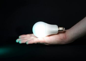 Žmogus laikantis ranką su lemputėmis tamsoje