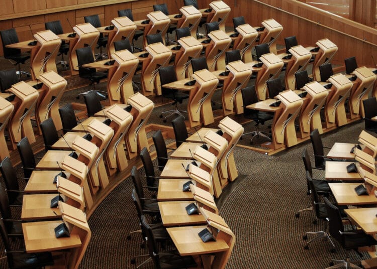 Horizontalus kadras kuriame matomi stalai Škotijos parlamento pastato viduje seimas
