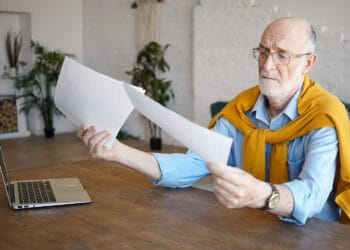 šešiasdešimtmetis vyras rankose laikantis dokumentus 3 pakopos pensijos nutraukimas